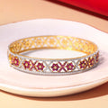 Gold bracelet with ruby gemstones on a white plate