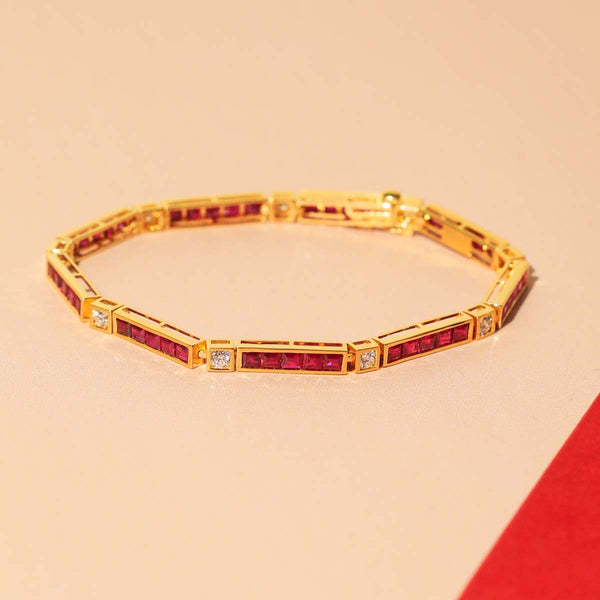 Gold bracelet with ruby stones on a beige background