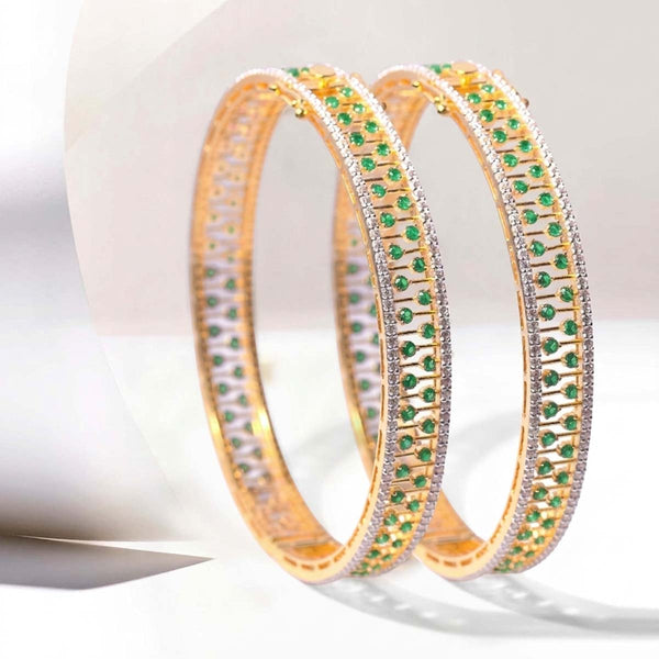 Gold bangles with emerald gemstones on a white background