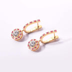 Gold hoop earrings with gemstones on a light pink background