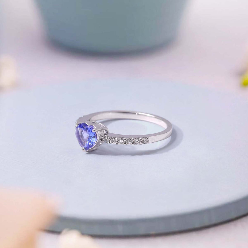 Silver ring with a heart-shaped blue gemstone on a light blue surface