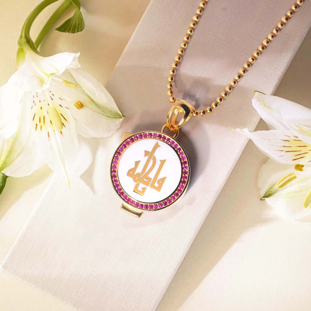 Gold necklace with a circular pendant featuring initials, surrounded by white flowers on a light background